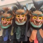 Nahaufnahme von drei traditionell gekleideten Fasnetsfiguren mit kunstvoll geschnitzten Masken und farbigen Stoffschuppen.