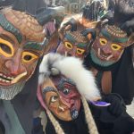 Nahaufnahme mehrerer Fasnetsfiguren mit detailreichen Holzmasken und traditionellen Häs während eines Straßenumzugs.